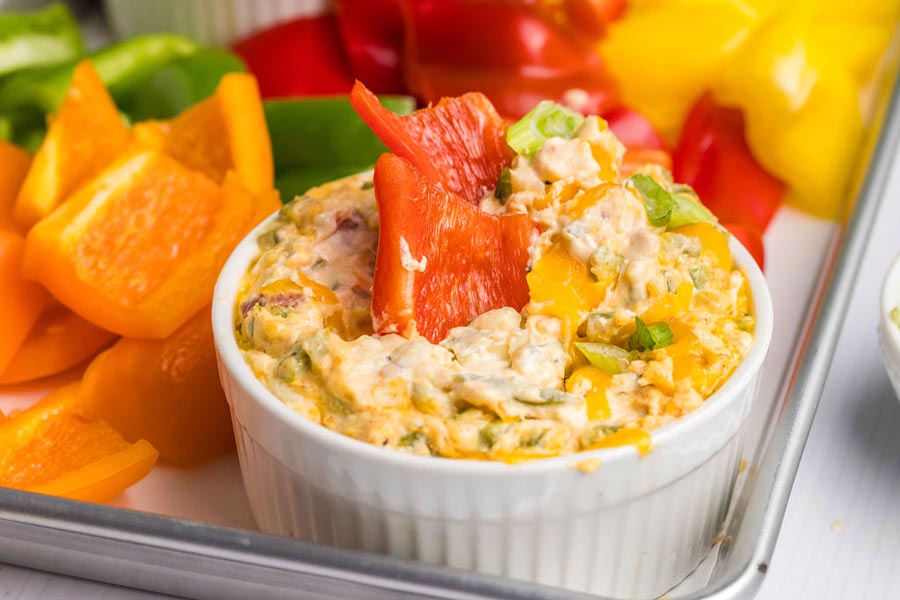 Slices of bell pepper sitting in a creamy dip.