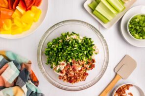 Diced jalapeno and crumbled bacon in a bowl with other dip ingredients.