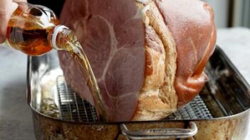 Pouring filtered apple cider vinegar in a roasting pan with a ham inside.
