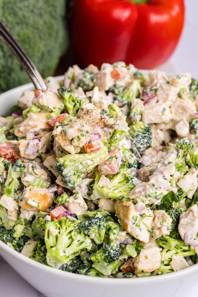Close up of chunks of broccoli florets and chicken tossed in a creamy dressing.