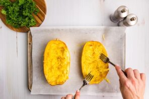 Shredding a spaghetti squash into noodles with two forks.