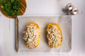 Roasted spaghetti squash on a baking tray and stuffed with chicken and blue cheese mixture.