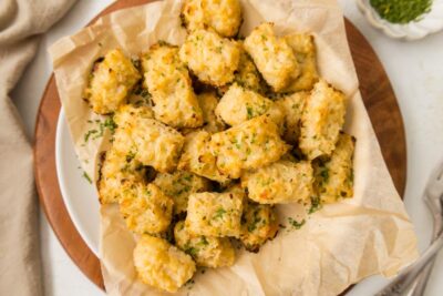 A pile of cauliflower tots in a bowl covered with parchment.