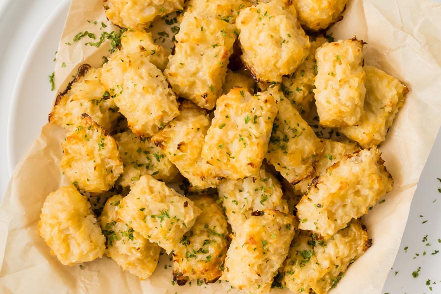 Close up of cauliflower tater tots with parsley sprinkled on top.