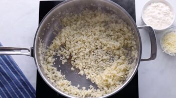 Cauliflower rice cooking in a skillet.