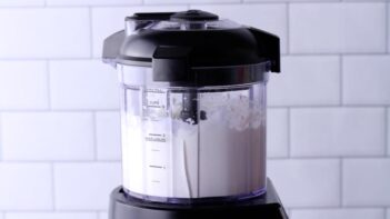 A food processor with blended cottage cheese inside.