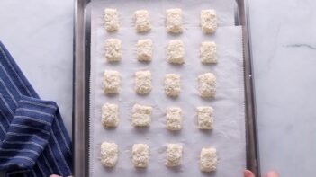 Cauliflower tots molded into tot shapes on a baking tray.