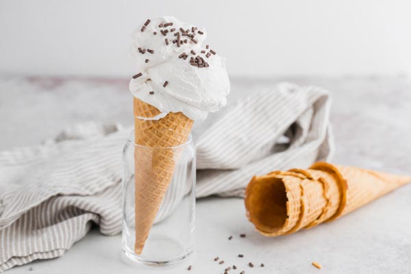 a cone with vanilla ice cream topped with chocolate sprinkles lying next to empty cones