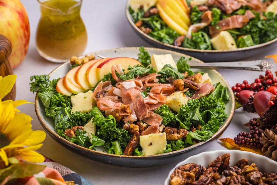 A bowl of prosciutto, brie and apple kale salad.