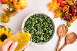 Pouring salad dressing over a kale salad.