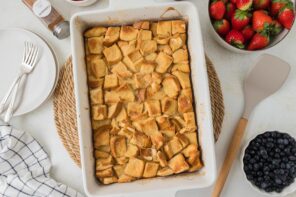 Baked french toast casserole on the table with fresh berries nearby.