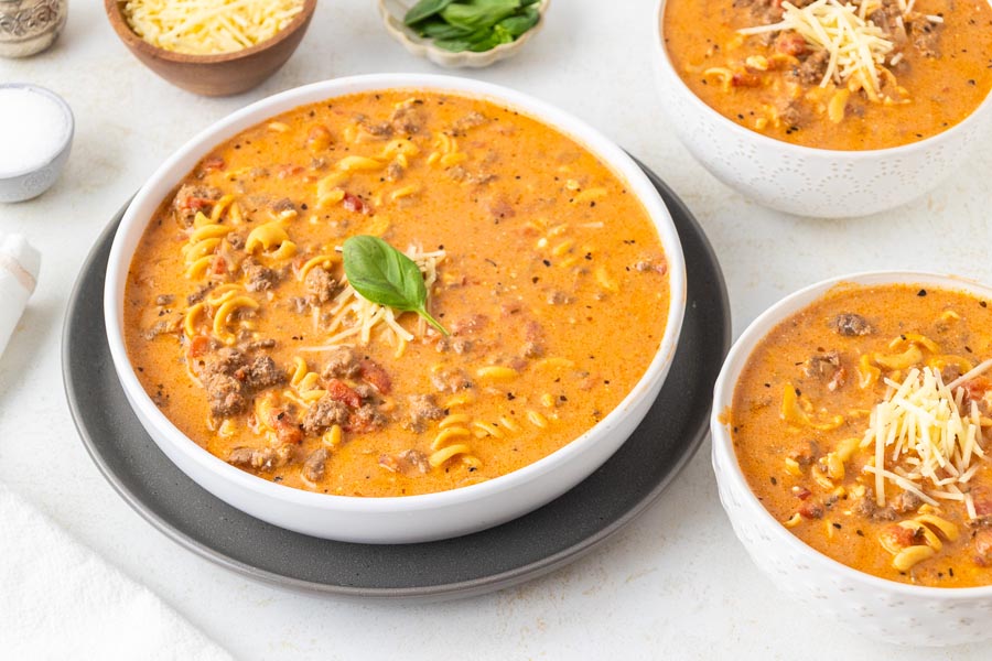 A couple bowls of creamy tomato soup filled with pasta and beef.