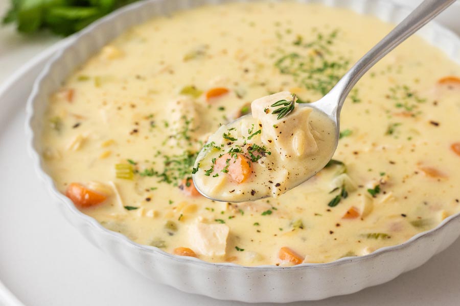 A spoonful of chicken and rice soup over a bowl.