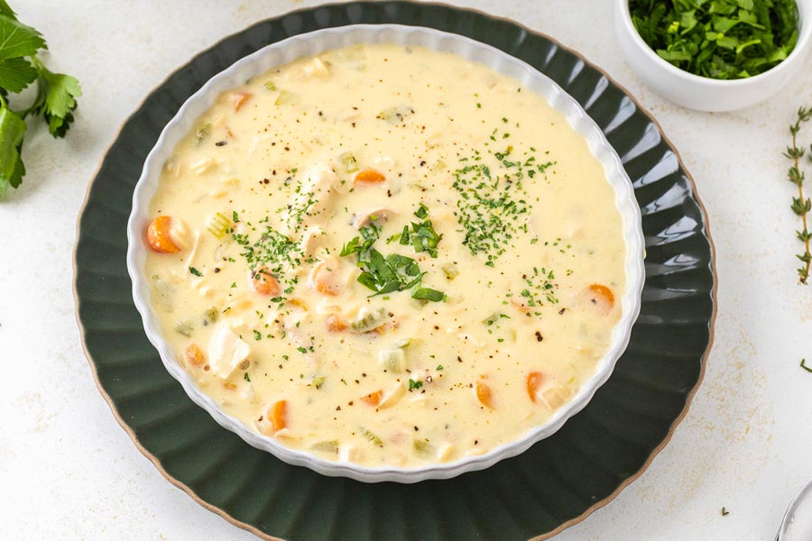 A bowl of low carb of creamy chicken and rice soup topped with fresh herbs.