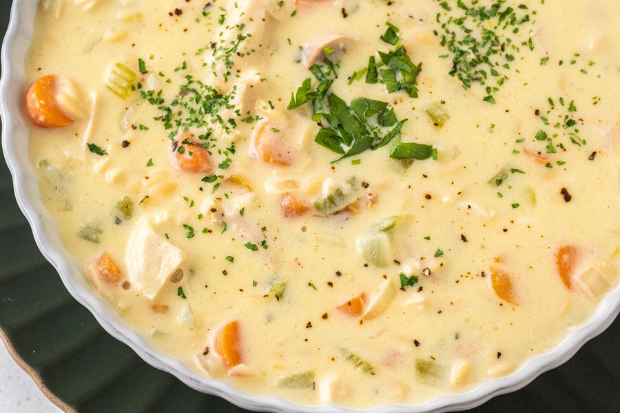 Close up of creamy chicken and rice soup topped with chopped parsley.