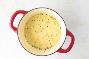 A pot of creamy chicken soup in a red dutch oven.