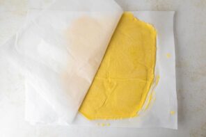 Pie dough rolled out to a thin circle and sandwiched between sheets of parchment paper.