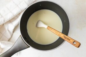 Cream and sweetener mixture in a saucepan with a spatula inside.