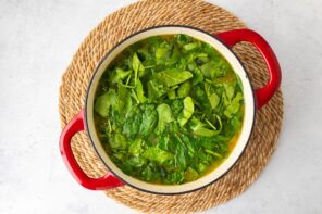 Spinach leaves wilting in a soup filled Dutch oven.