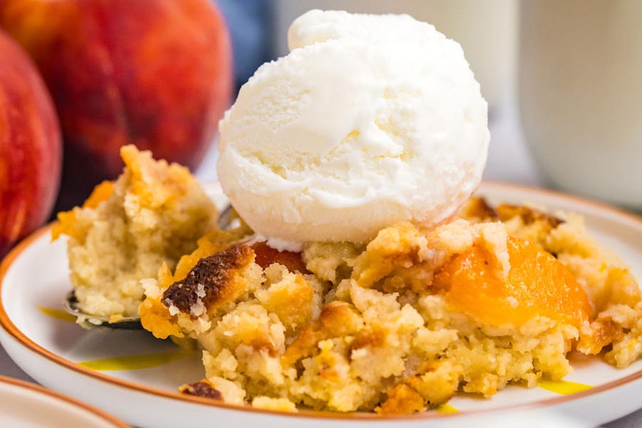 Close up of ice cream on top of a serving of peach cobbler.