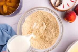 Pouring milk into dry ingredients to make a cobbler batter.