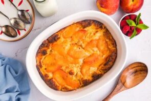 Baked peach cobbler in a white baking dish.