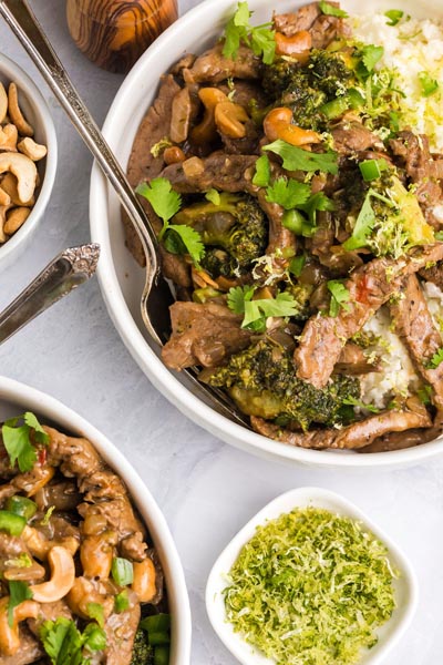 A low carb version of the half baked harvest recipe for cashew beef in a bowl topped with cilantro and jalapeno over coconut cauliflower rice.