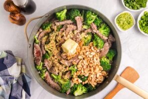 A skillet with steak, broccoli, cashews and butter inside.