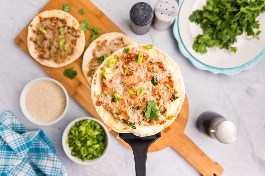 A spatula holding a smashed taco made with Chinese dumpling filling.