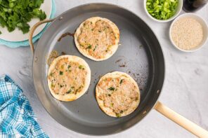 Three smashed tacos cooking in a skillet.