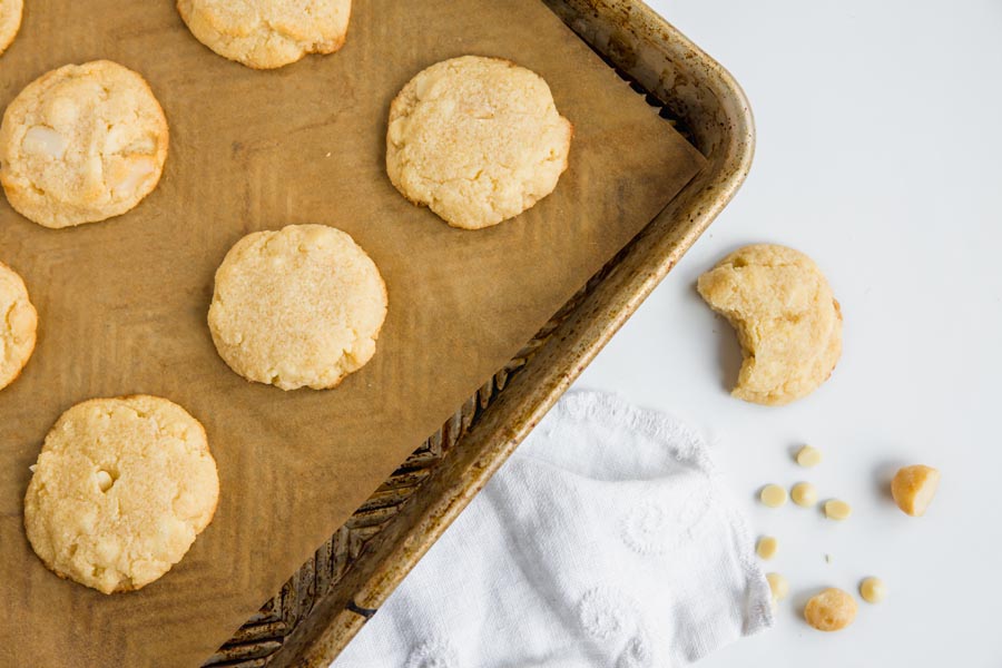 white chocolate macadamia cookies on a baking tray with a white towel