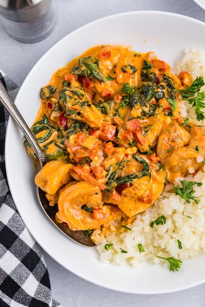 A plate of paprika shrimp served over rice and topped with parlsey.