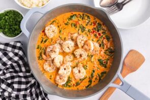 Cooked shrimp sitting in a creamy broth in a skillet.