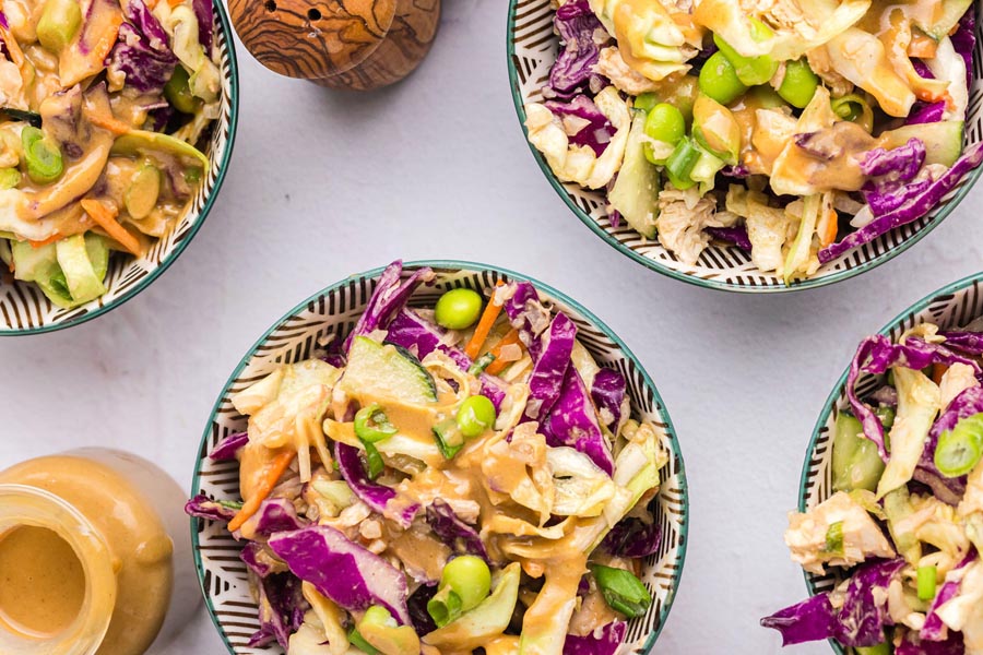 Multiple bowls of crunchy Thai salad with edamame and purple cabbage.