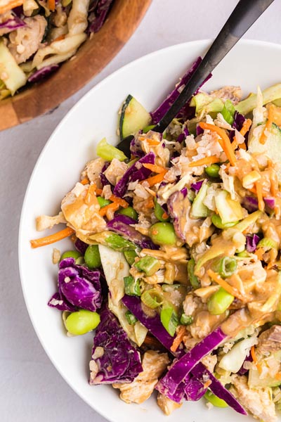 Creamy peanut thai dressing over a crunchy cabbage salad on a plate.